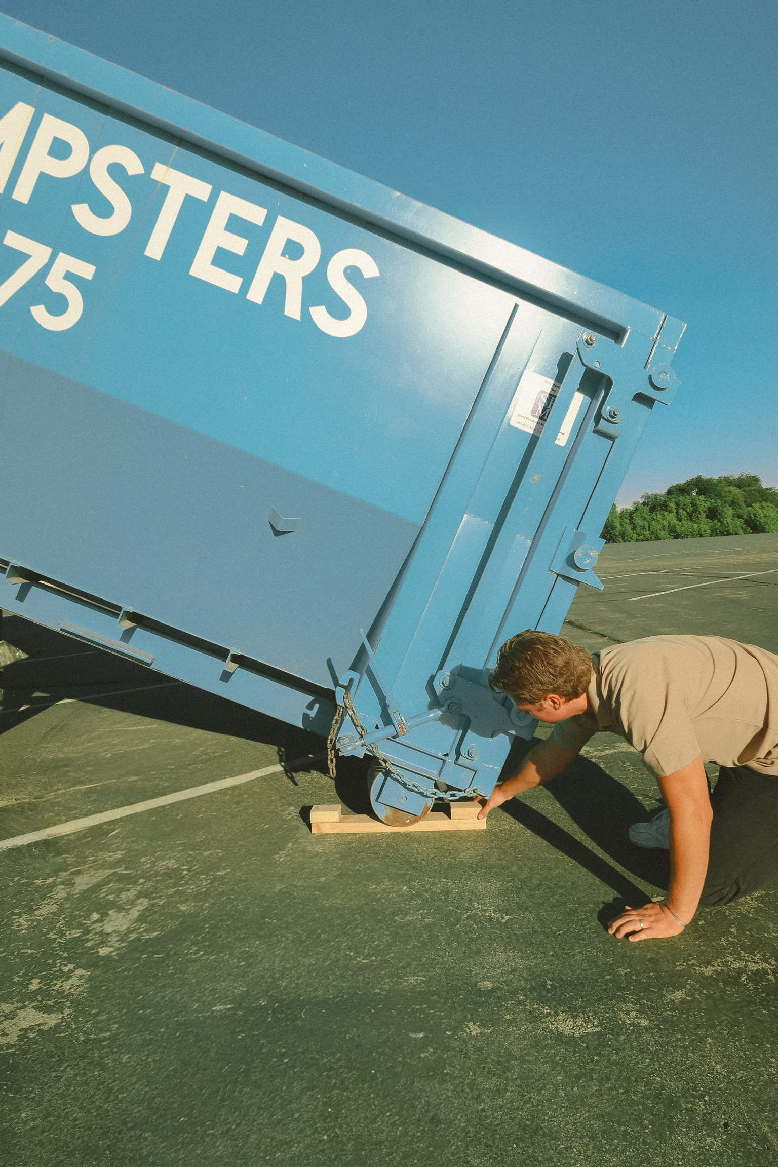 Blue Bin dumpster positioned carefully on driveway protection boards